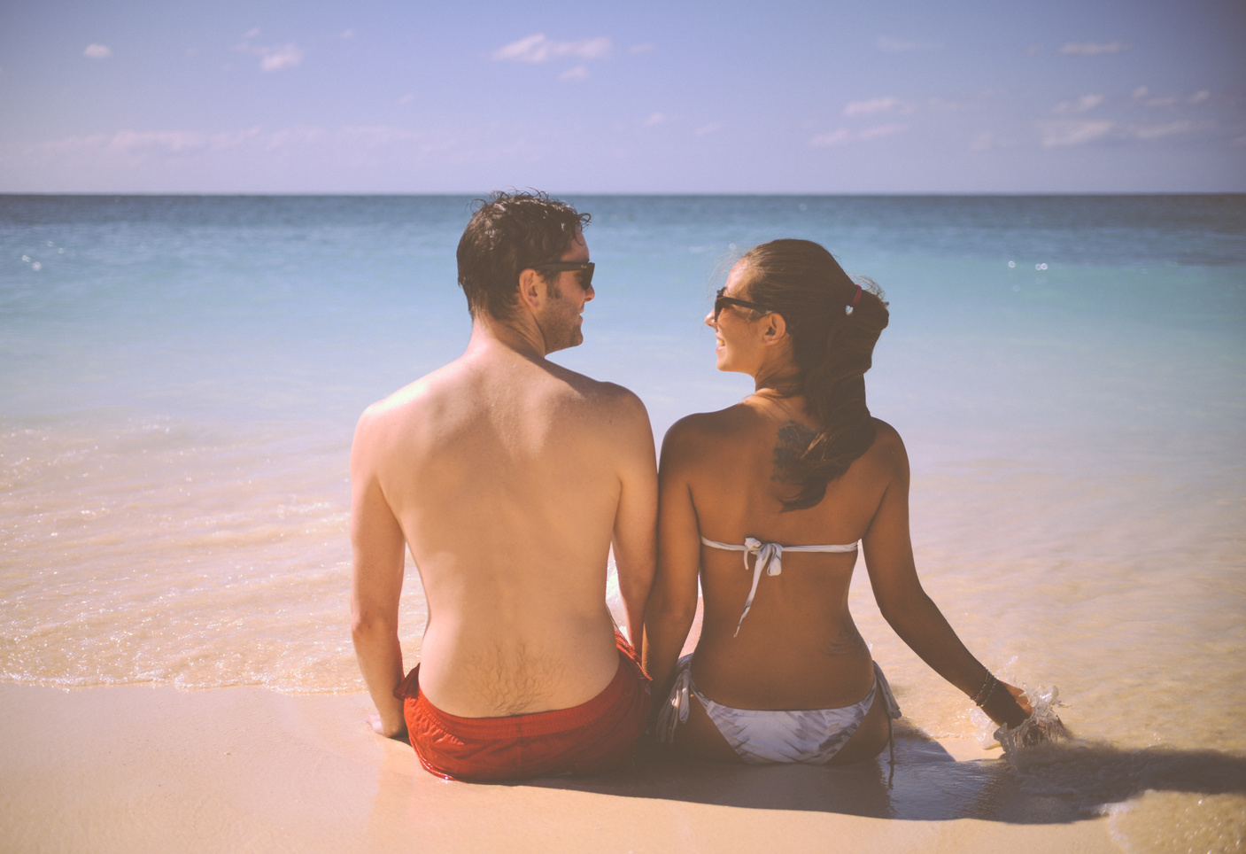 Man and Woman Sitting Beside Body of Water